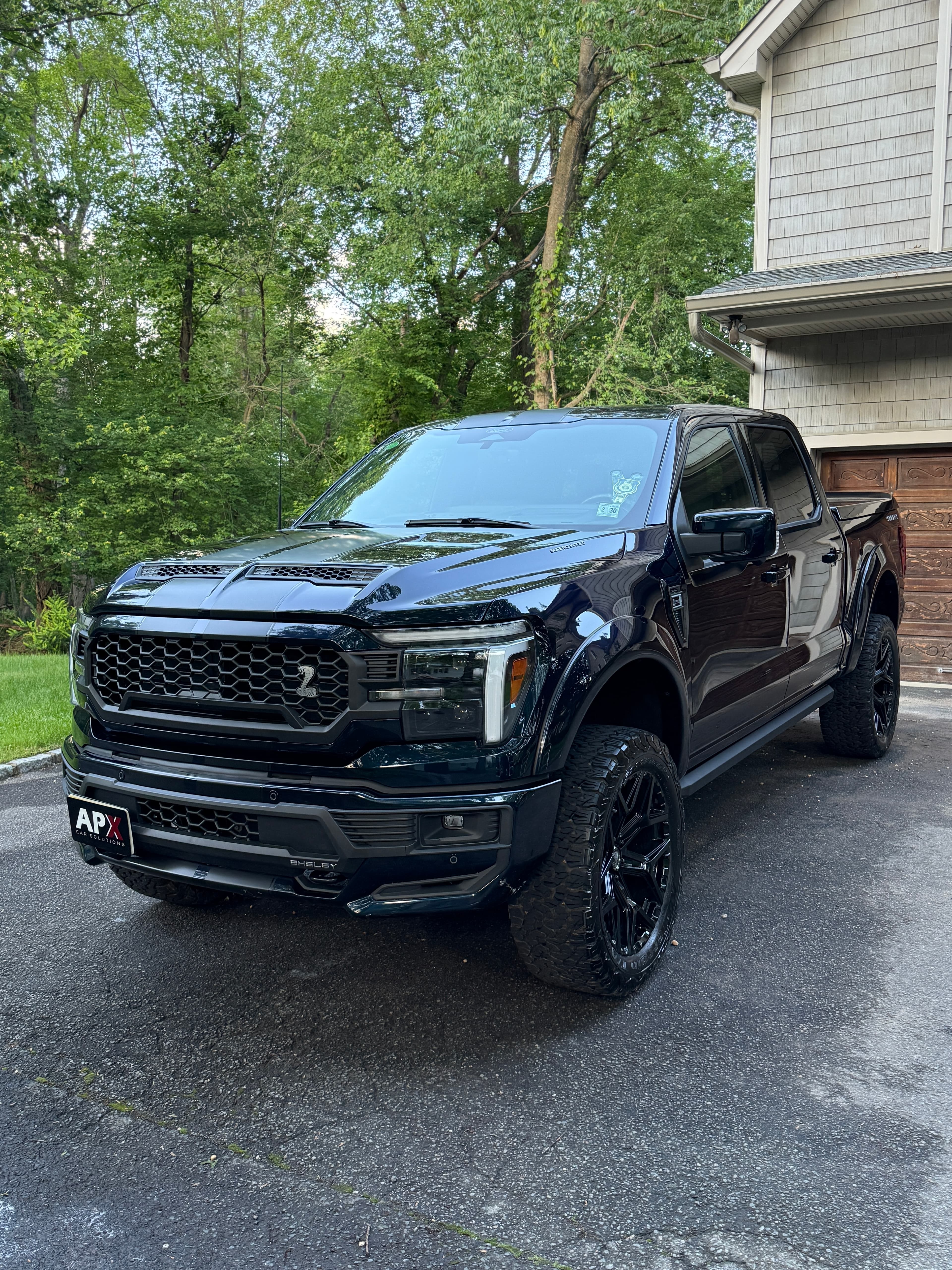 Lifted black Ford F-150 with a deep-gloss finish in a Saddle Brook driveway
