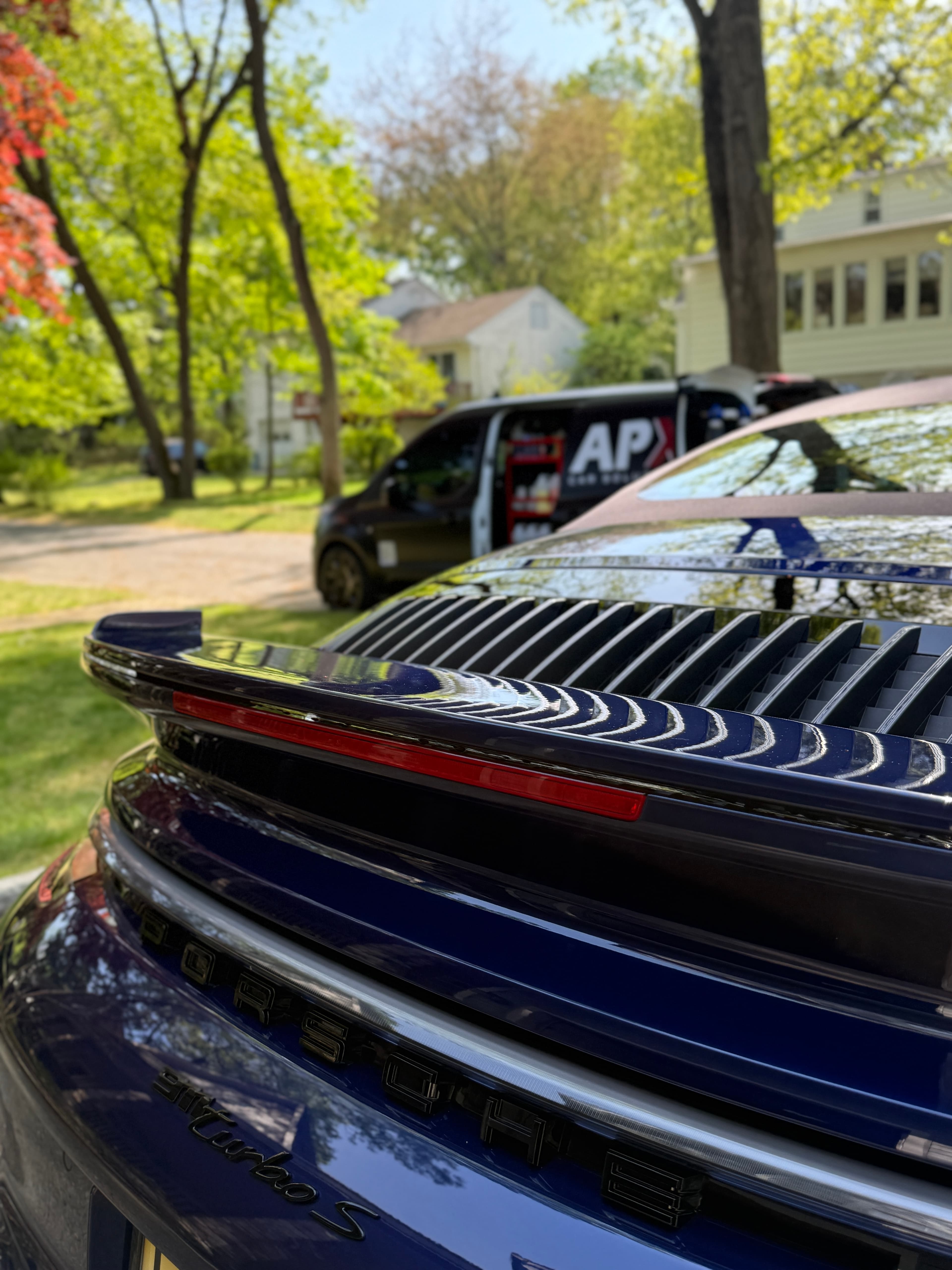 Rear wing of a blue Porsche 911 Turbo S detailed in Haworth with the APX van on site
